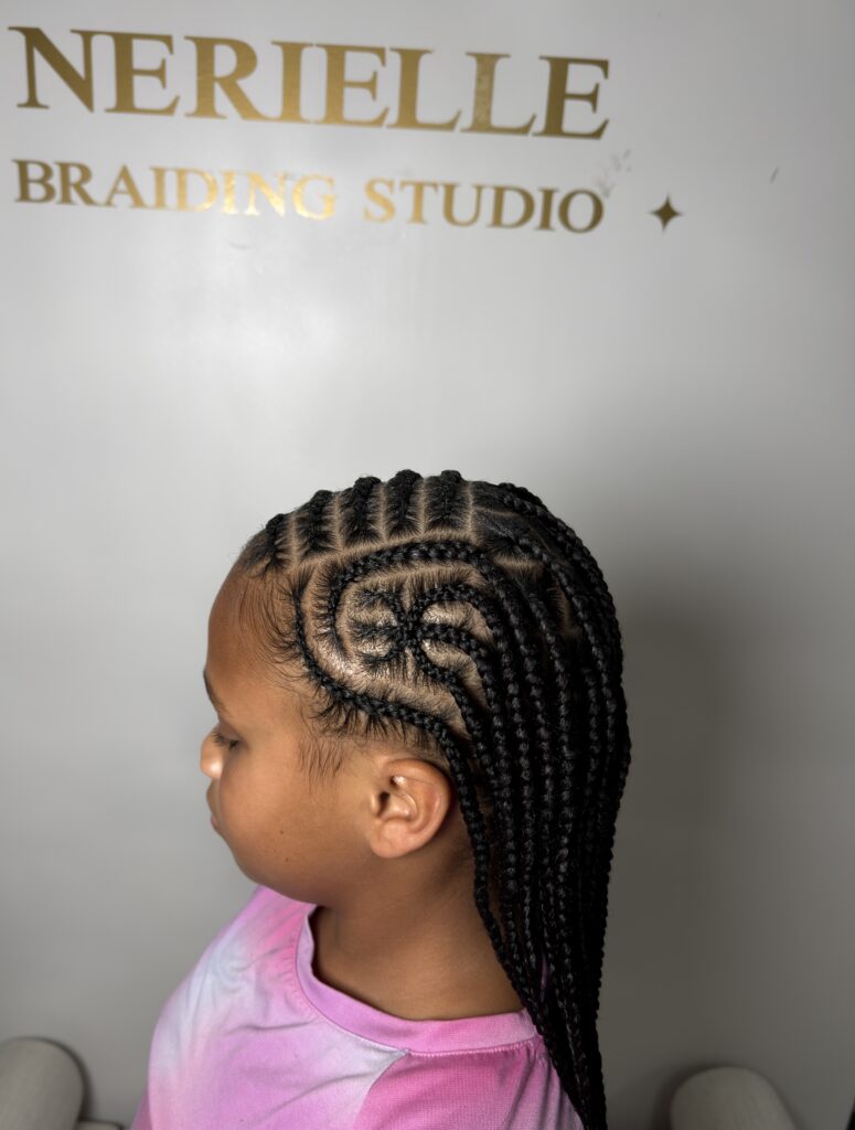 Side profile of a young girl with braided style in front of the Nerielle Braiding Studio logo wall