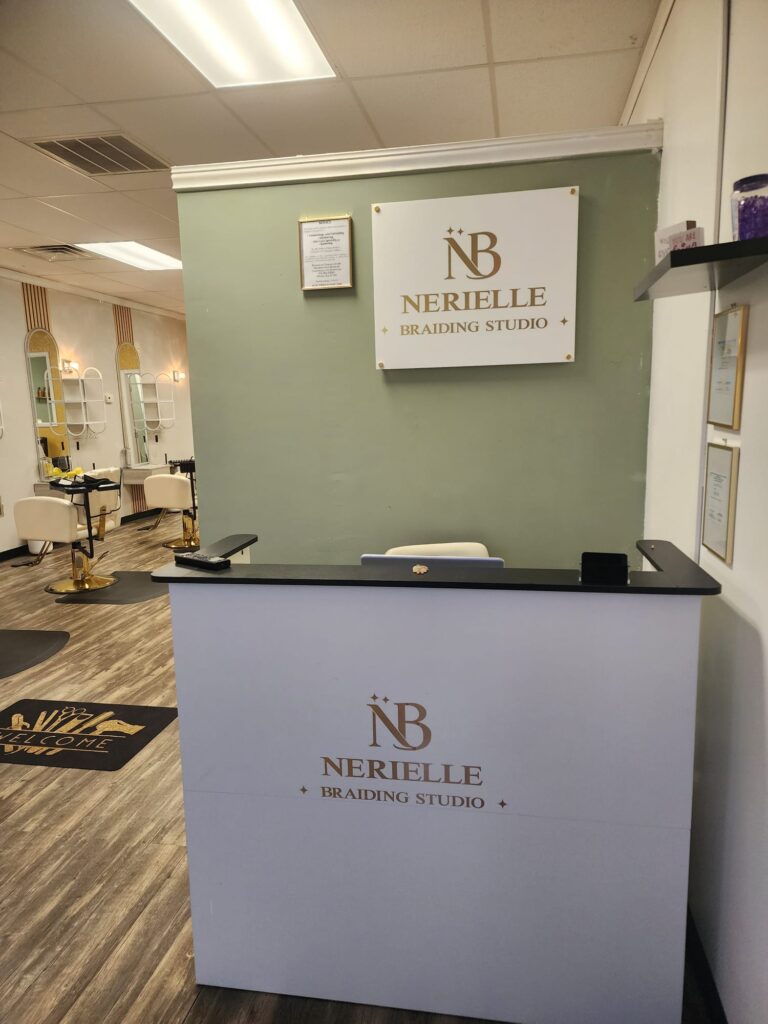 Nerielle Braiding Studio reception desk with sage green wall and gold NB Nerielle Braiding Studio signage
